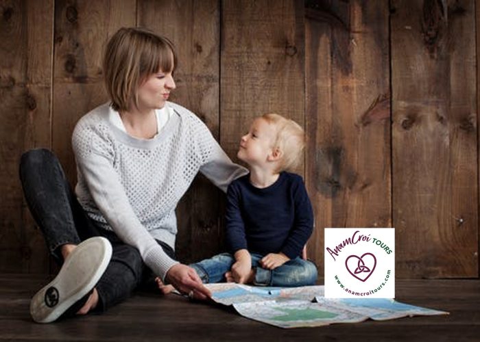 An adult and child sit on the wooden floor, map of Ireland spread before them, plotting their dream adventure with Custom Ireland Tours.